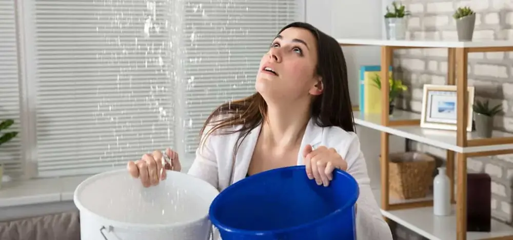 Water leaking from a ceiling into buckets during a plumbing emergency