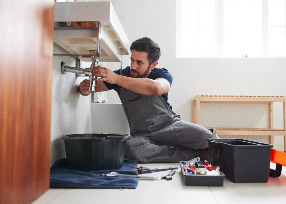 Plumber working with tools and plumbing components during a repair