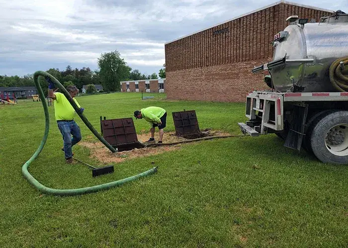 Septic service truck and crew pumping a septic tank on site