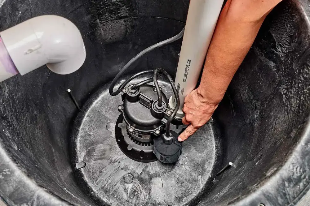 Technician servicing a sump pump inside a residential sump pit