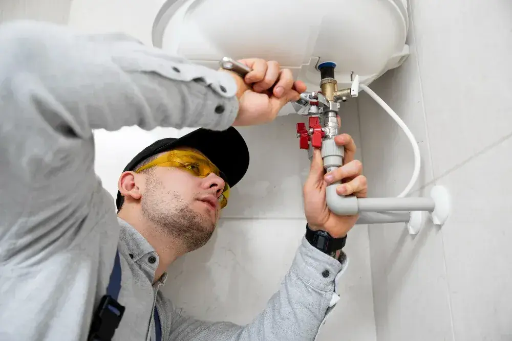 Technician adjusting shutoff valves on a residential water heater unit