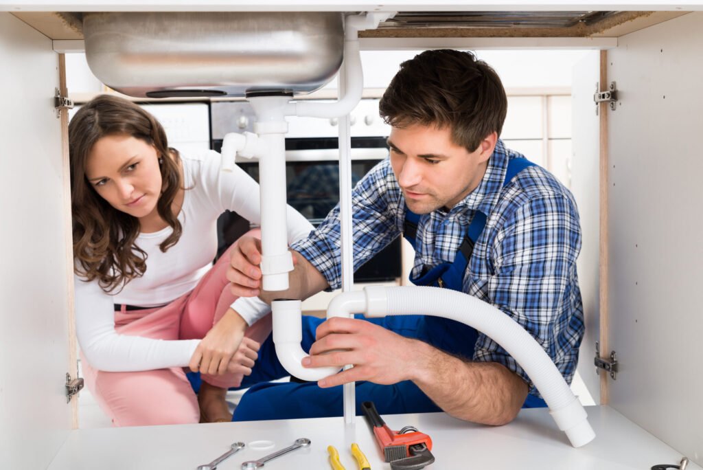 Young woman looking at male worker fixing pipe